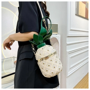 Detail of unique pineapple crossbody bag with gold rivet grid and green leaf trim