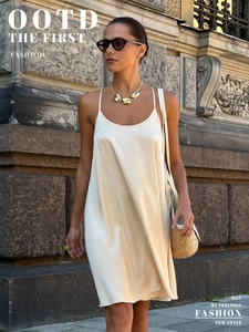 Detail of champagne satin camisole dress with thin straps and glossy silk texture
