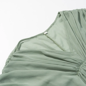 Detail des V-Ausschnitts mit feinen Falten und S-Größenetikett am salbeigrünen Kleid