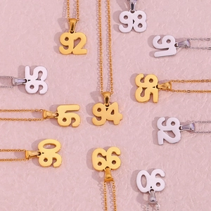 Detail shot of gold and silver numbered pendants on a textured pink background