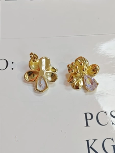 Detailed close-up showing gold floral earrings with crystal drop and pin back structure
