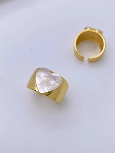 Detail of gold-plated rings showing a heart-shaped shell inlay and a sleek open band