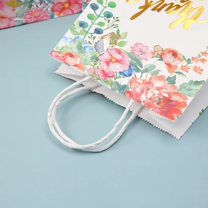 Detailed close-up of a white gift bag with pink floral patterns and gold Thank You text