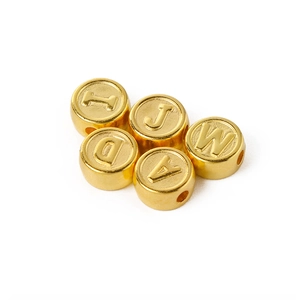 Macro view of gold-plated acrylic alphabet beads featuring engraved letters for DIY jewelry