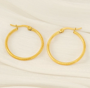 Close-up of 18k gold plated hoop earrings with spiral texture on white silk background