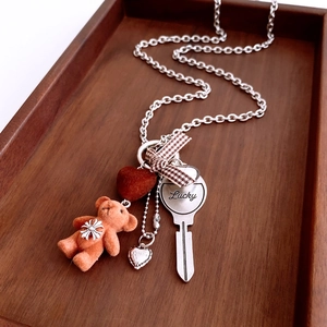 Close-up of titanium steel chain with flocked bear, velvet heart and key charms