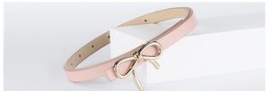 Detail of light pink PU leather belt featuring a golden metal bow buckle for women