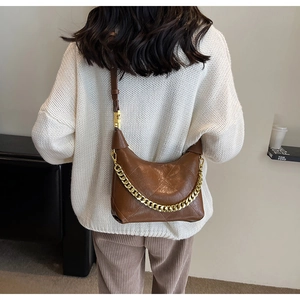 Detailed view of a brown quilted bucket bag featuring a thick gold chain and leather strap