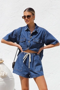 Detail of dark blue denim set showing button shirt pockets and drawstring shorts