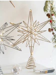 Close-up of golden metal star tree topper with glitter and LED string lights details