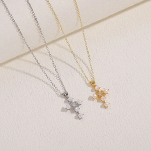 Elegant gold and silver cross necklaces with pearl and zircon charms on beige background
