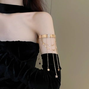 Detail of gold arm cuff with multiple delicate fringe chains and dangling star charms