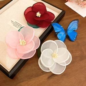 Floral and butterfly hair clips in red, pink, and white on a wooden and cream jewelry tray