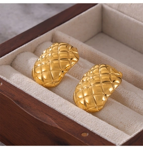 Macro detail of gold-plated titanium earrings with elegant quilted rhombic pattern design