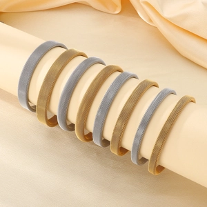 Dettaglio di bracciali a maglia intrecciata in oro e argento su un supporto lussuoso