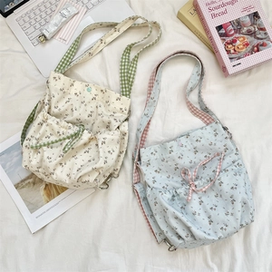 Detail of floral canvas crossbody bags with drawstring and plaid woven straps in a cozy setting