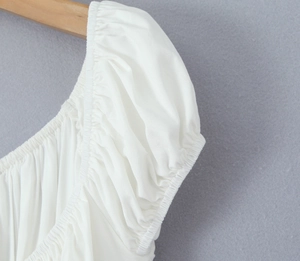 Détail des manches bouffantes blanches et de l'encolure froncée sur une robe courte