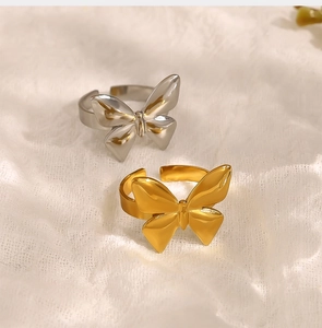Detailed view of silver and gold bow-shaped open rings on white textured fabric