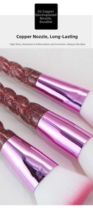 Close-up of makeup brushes featuring pink gradient bristles and transparent spiral handles