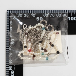 Detailed view of men's pearl and chain necklace with lightning bolt pendant and scale ruler