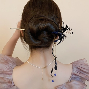 Detail of floral hair pin with golden tassels and blue beads in an elegant bun