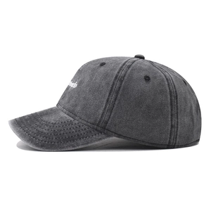 Gros plan de la broderie blanche sur une casquette en coton gris foncé délavé vintage