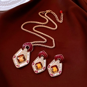 Detailed shot of vintage gold jewelry set with amber gemstones on red silk fabric