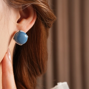 Vista dettagliata dell'orecchino tondo blu con bordo argentato su modella femminile