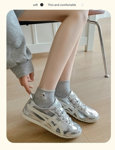 Close-up of silver metallic sneakers worn with cute embroidered puppy cotton socks