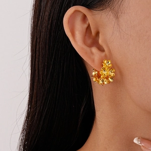Elegant gold flower C-shaped metal earrings worn by a model in a side profile shot