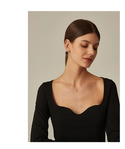 Close-up of gold cross necklace and earring set with zircons on a model in black top