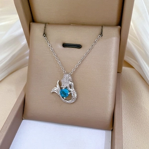 Macro view of silver mermaid pendant with round blue sapphire and micro-pave diamonds