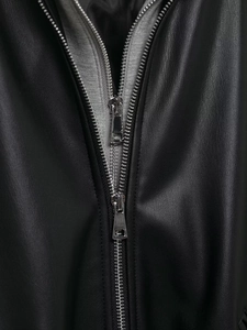 Detailed macro view of the premium dual-way metal zipper on black leather jacket