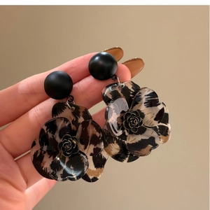 Close-up of leopard print flower earrings with black matte studs and gold floral centers