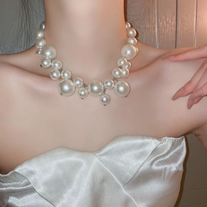 Close-up of elegant mixed-size white pearl necklace on model for a trendy chic style