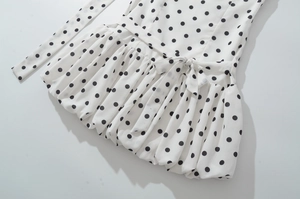 Detailansicht des weißen Polka-Dot-Minikleides mit Taillengürtel und gefaltetem Saum