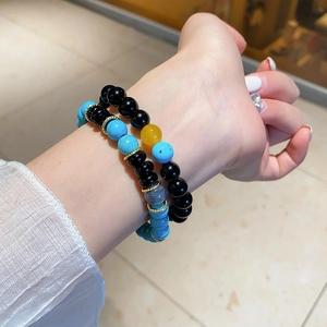 Detail of stacked turquoise and black agate beaded bracelets with gold metal spacers