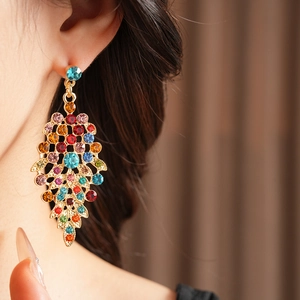 Detail of vintage gold leaf earrings with colorful rhinestones on a female model