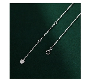 Macro shot of S925 sterling silver stamp and heart-shaped pendant on chain link
