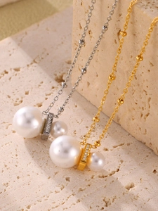 Detail of silver and gold stainless steel necklaces with pearls and zircon insets