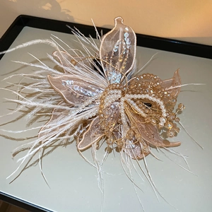 Detail of handmade butterfly clip with feathers, pearls and beads in champagne tones