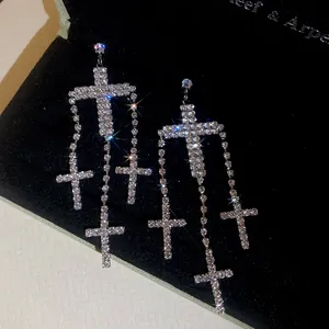 Macro detail of silver cross tassel earrings with sparkling rhinestones on black velvet
