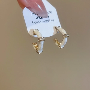 Detail of silver needle C-shaped hoop earring with white enamel and sparkling zircons