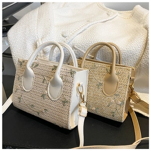 Close-up of straw woven bags with floral embroidery and adjustable PU shoulder straps