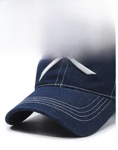 Detailed close-up of dark blue denim baseball cap brim with white triple decorative stitching