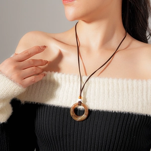Detail of a vintage resin round pendant on brown cord shown on a female model