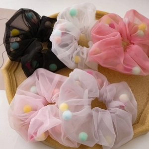 Five colorful mesh hair scrunchies filled with rainbow balls on a yellow tray