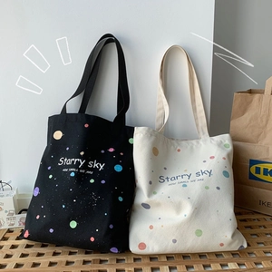 Détail de sacs fourre-tout en toile avec imprimé ciel étoilé en noir et blanc cassé