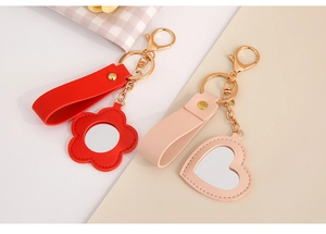 Close-up of red flower and pink heart PU leather keychains with integrated mini mirrors