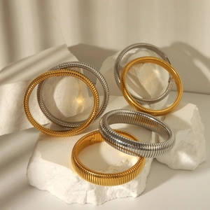 Detail of vintage gold and silver Tubogas bracelets on white stone with elegant lighting